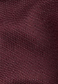 Tessuto bordeaux con una trama testurizzata a motivo a diamante, caratterizzato da un raffinato disegno a griglia in tonalità più scure, che crea una profondità sottile.