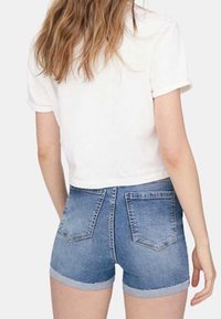 Vit kortärmad croppad t-shirt som matchas med ljusblå denimshorts med uppvikt nederkant och två bakfickor.