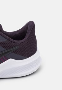 Chaussure de sport violette avec une tige en maille texturée, des accents noirs et une semelle blanche texturée, dotée d'un talon rembourré pour un bon soutien.