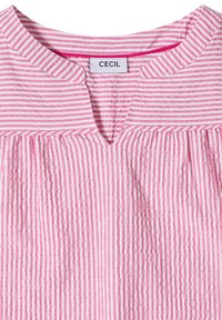 Camisa a rayas verticales en rosa y blanco con un escote partido y una etiqueta de la marca "CECIL" cosida dentro del cuello.