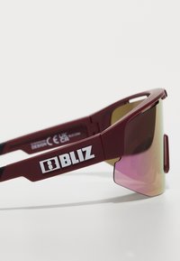 Burgundowe sportowe okulary przeciwsłoneczne z gradientowymi różowymi soczewkami, o opaskowym designie, z wyraźnym białym logo "BLIZ" na zausznicy.