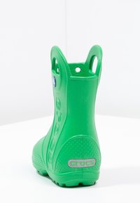 Botte en caoutchouc verte avec une surface texturée, forme arrondie, trous de ventilation sur les côtés et un logo près du talon avec un accent argenté.