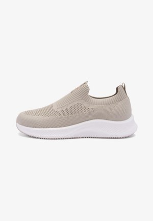Zapatilla tipo slip-on de punto color beige claro con suela gruesa blanca y cuello elástico acanalado, diseñada para comodidad y uso casual.