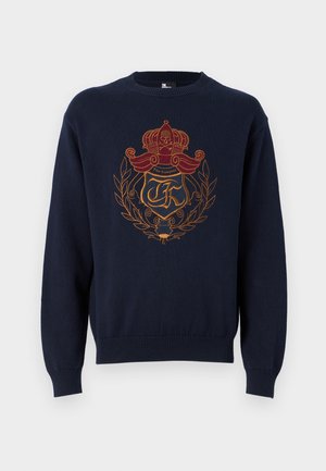 Navy blue knitted sweater featuring an ornate embroidered motif in red and gold, including a crown and laurel design. Round neckline and long sleeves.