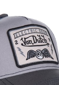 Casquette grise avec un patch noir et blanc portant "Von Dutch", des ailes et des motifs d'éclairs, avec une couronne structurée et une visière courbée.