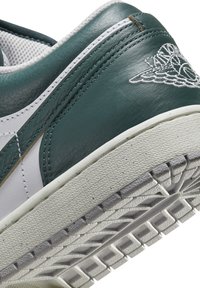 Gröna och vita lädersneakers med strukturerad yta, framträdande gummisula och broderade detaljer på hälen.