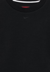 Melns kokvilnas T-krekls ar apaļu kakla izgriezumu, ar mazu melnu Nike logotipu uz krūtīm un daudzkrāsainu svītru iekšējo kakla daļu.