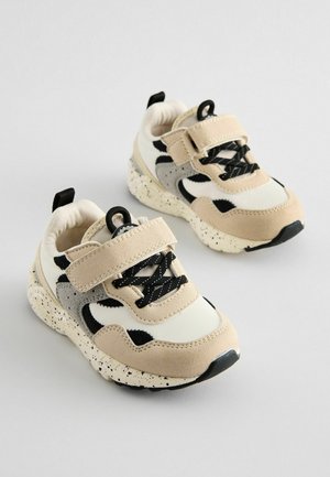 Beige og sorte sneakers med velcrorem, tekstureret overdel, spraglet sål og kontrasterende mønstre på siderne. Velegnet til aktiv beklædning.