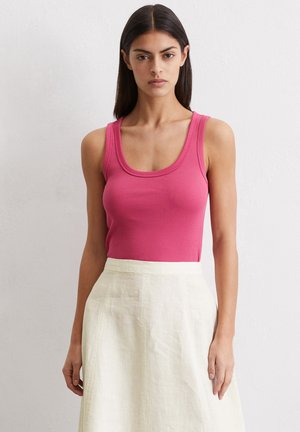 Geribbelde, mouwloze tanktop in felroze. Gecombineerd met een crèmekleurige linnen rok tot de knie met een subtiele textuur.