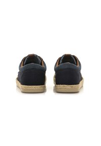 Zapatillas de lona navy con una suela de yute trenzado, que presentan un acento en marrón claro en el talón. Parte superior redondeada y material suave y texturizado.