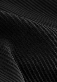 Black ribbed fabric with a textured surface, showcasing parallel lines and a soft appearance, indicating stretch and density.