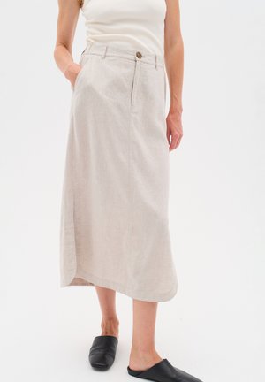 Vaal beige linnen rok met een zijsplit, twee zakken, een knoopsluiting aan de voorkant en een relaxte pasvorm. Gecombineerd met zwarte instapschoenen.