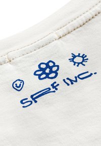 Biała bawełniana tkanina z niebieskimi nadrukowanymi grafikami, w tym uśmiechnięta buźka, kształt kwiatu oraz napis "SRF INC." Wyróżniające się przeszycia przy dekolcie.