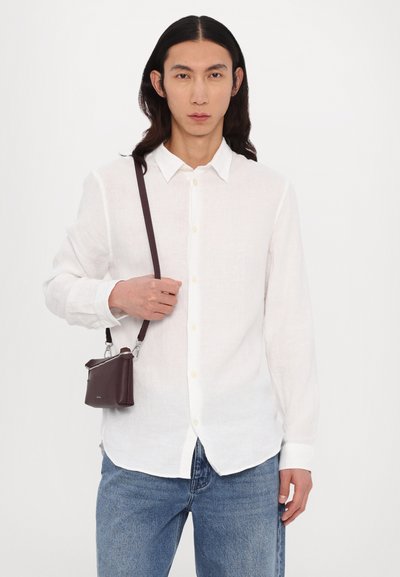 White linen long-sleeve shirt with button closure, paired with blue denim jeans and a small burgundy crossbody bag featuring silver hardware.