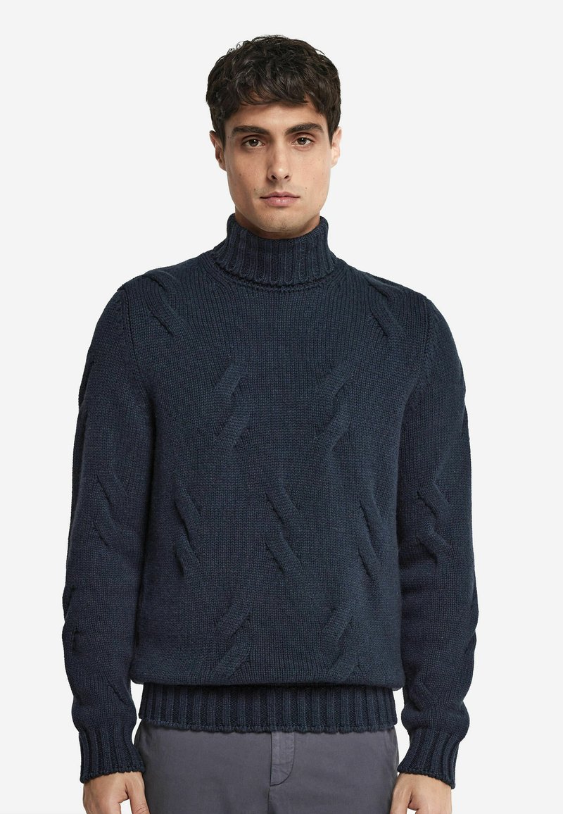 Mörkblå stickad polotröja med texturerade mönster och ribbade muddar och nederkant. Enkel, över huvudet-design. Mjuk, chunky tyg.