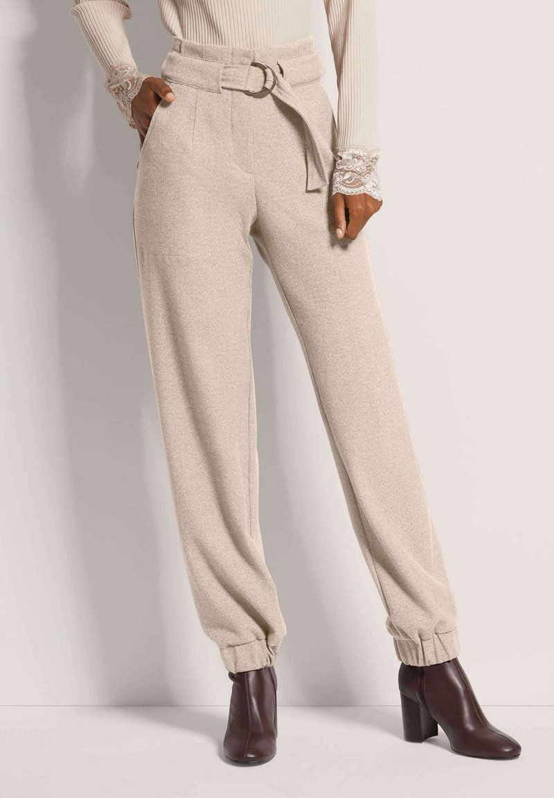 Beige wijde broek met een aansluitende taille, riem met een metalen gesp en manchetten aan de enkels. Zachte textuur, op maat gemaakte pasvorm, zijzakken.