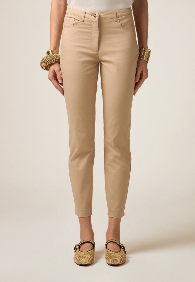 Beige slim-fit broeken met voorzakken, rits en een gladde textuur. Draag ze met geweven instappers die een minimalistisch ontwerp uitstralen.