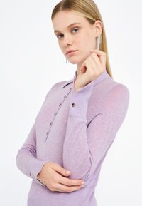 Polo a manica lunga in lavanda con colletto, patta con quattro bottoni e polsini con dettaglio a bottone. Tessuto morbido e leggero.