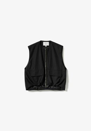 Crna kratka prsluk s patentnim zatvaračem sprijeda, dizajnom bez rukava, dva prednja džepa i skupljenim rubom. Izrađen od glatkog materijala s mat završetkom.