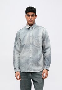 Džínová košeľa s vyblednutou svetlomodrou a šedou farebnou paletou, s golierom na zapínanie, prednou vreckom a textúrovanou látkou.