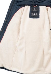 Marinblå utomhusjacka med en beige plyschfoder, med en etikett vid kragen och röda accentstyg på kanterna.