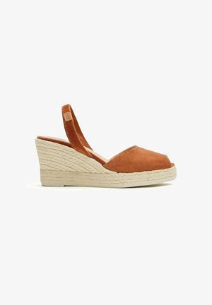 Sandalias de cuña de ante marrón con puntera abierta, correa tipo slingback y suela de plataforma de cuerda trenzada. Presentan una forma redondeada y una textura suave.