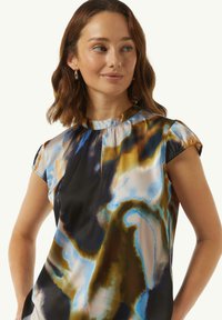 Mehrfarbige Bluse aus leichtem, glänzendem Stoff mit hohem Kragen, kurzärmeligen Kappen und abstrakten Mustern in Blau, Braun und Schwarz.