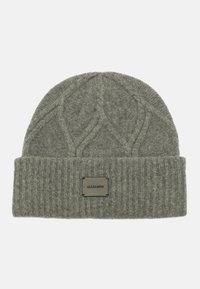 Gorro de lana gris con un patrón texturizado en la parte superior y un puño acanalado. Presenta una etiqueta rectangular con texto negro.