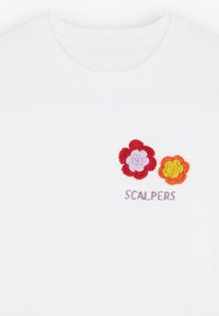 T-shirt bianca con fiori ricamati in rosso, viola e arancione, con la parola "SCALPERS" in testo viola sotto il design.