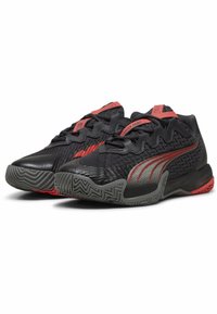 Zapatos deportivos negros con un upper texturizado, acentos rojos, patrón de zigzag y una suela de goma flexible con un diseño de tracción.