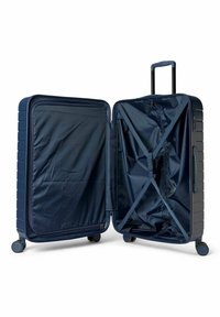 Valise rigide bleu marine avec rainures horizontales, deux compartiments, poche en filet zippée, sangles de compression et poignée rétractable sur le dessus.