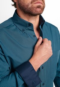 Teal- en marineblauw geruit overhemd met knopen, een gestructureerde kraag, donkere manchetten en bijpassende knopen, met een gladde stoftextuur.