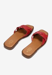 Sandalias rojas de cuero tipo slip-on con un diseño de tira trenzada, punta cuadrada y una plantilla texturizada en marrón. Presenta una suela plana y un discreto detalle de logo.