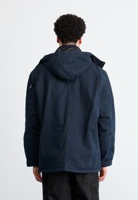 Marineblaues Kapuzenjacke mit glatter Textur und Seitentaschen. Verfügt über einen Frontreißverschluss und kontrastierende Innenfutterdetails.