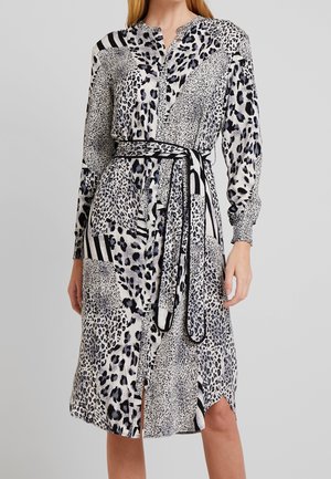 Vestido de manga larga que presenta una mezcla de patrones de leopardo y rayas en negro, blanco y gris. Incluye un cinturón para ajuste y una abertura lateral.