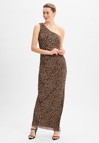 Robe maxi à une épaule en imprimé léopard, présentant une silhouette ajustée et un tissu fluide. Des accents noirs avec des talons à lanières complètent l'ensemble.