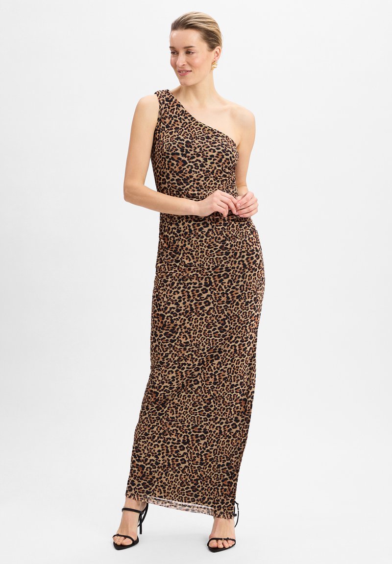 Robe maxi à une épaule en imprimé léopard, présentant une silhouette ajustée et un tissu fluide. Des accents noirs avec des talons à lanières complètent l'ensemble.