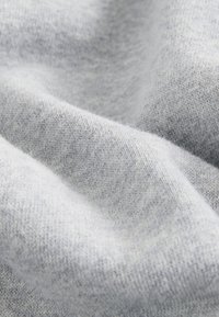 Hellgrauer, weicher, gestrickter Stoff mit feiner Textur, leichten Falten und sichtbaren Webmustern.
