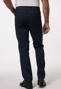 Marinblå byxor i bomull med rak passform, bakfickor och diskreta sömdetaljer. Bärs med svarta skor.