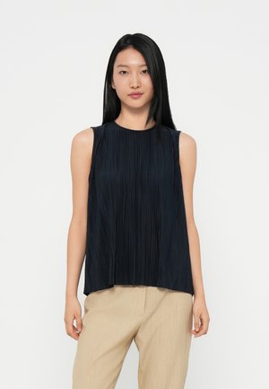 Navy pleated sleeveless top with a round neckline; lightweight fabric with a soft texture. Worn with beige, slightly textured trousers.