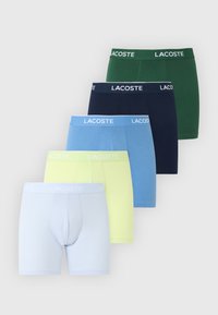 Πέντε ζευγάρια μποξεράκια Lacoste σε πράσινο, ναυτικό, μπλε, κίτρινο και ανοιχτό μπλε, στοιβαγμένα κάθετα σε λευκό φόντο.