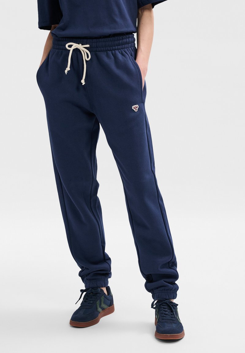 Pantaloni della tuta blu navy con vita elastica e coulisse, dotati di tasche laterali e polsini a costine. Piccolo logo ricamato sul davanti.