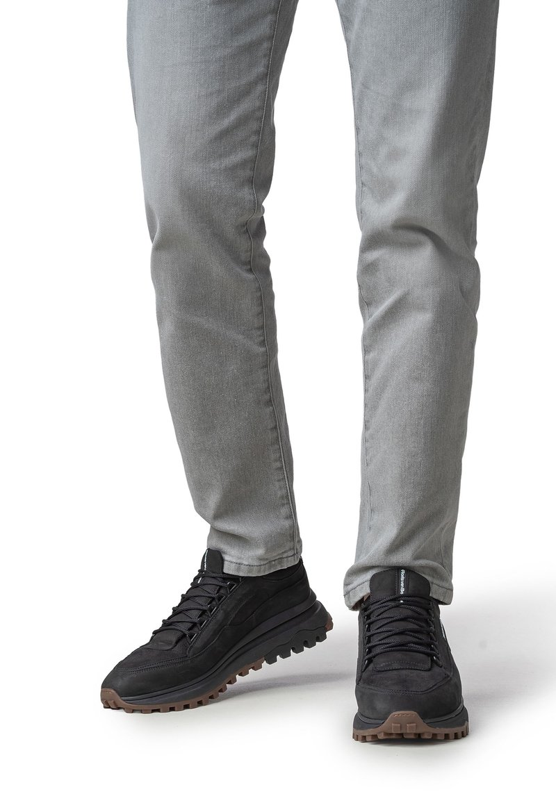 Musta tennarit, joissa on teksturoitu päällinen, nauhallinen malli ja kestävä kumipohja. Yhdistetty vaaleanharmaisiin, hieman istuviin farkkuihin.