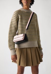 Crossbody bag featuring a pink top flap and a black base, with a smooth texture and a detachable strap attached by metal hardware.