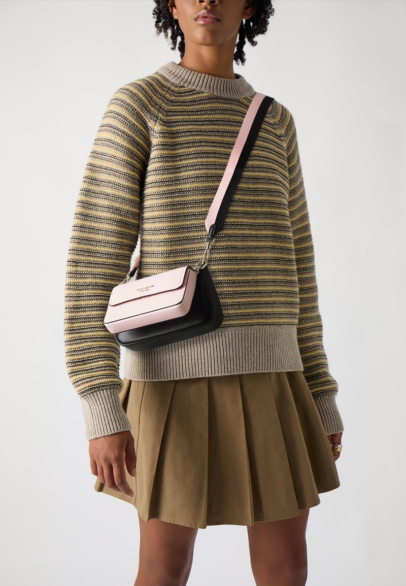 Crossbody bag featuring a pink top flap and a black base, with a smooth texture and a detachable strap attached by metal hardware.