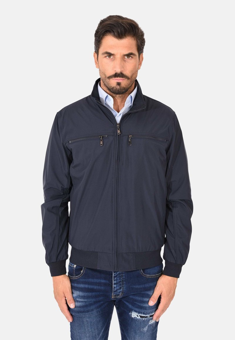 Giacca bomber blu navy con zip frontale, due tasche sul petto, polsini e orlo a coste, e un tessuto liscio e leggero.