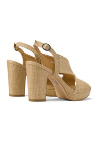 Tacones de plataforma color crema con detalles de tela trenzada, una correa ajustable en el tobillo y tacones cuadrados para estabilidad y altura.
