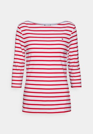 Wit shirt met lange mouwen en rode horizontale strepen, met een klein geborduurd logo op de bovenste linkerborst.