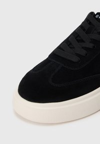 Must musta sussak, millel on sile ülemine osa, ümar varvas ja ühes toonis paelad. Omab paksu valget kummist tallat, millel on tekstureeritud viimistlus.