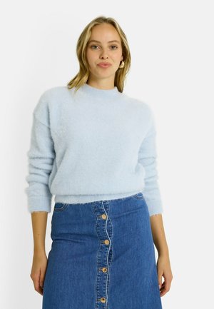 Un pull moelleux bleu clair avec un col rond et des manches longues, associé à une jupe en denim avec un devant à boutons.